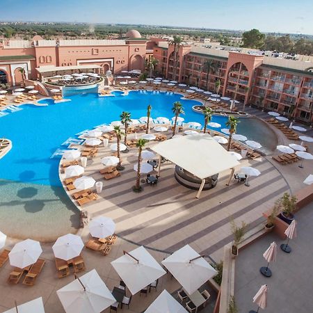 Savoy Le Grand Hotel Marrakech Marakeş Dış mekan fotoğraf The photo shows a large, luxurious hotel resort with a spacious swimming pool at its center. The pool area features several lounge chairs and umbrellas arranged around the water, providing a relaxing atmosphere for guests. Surrounding the pool are la