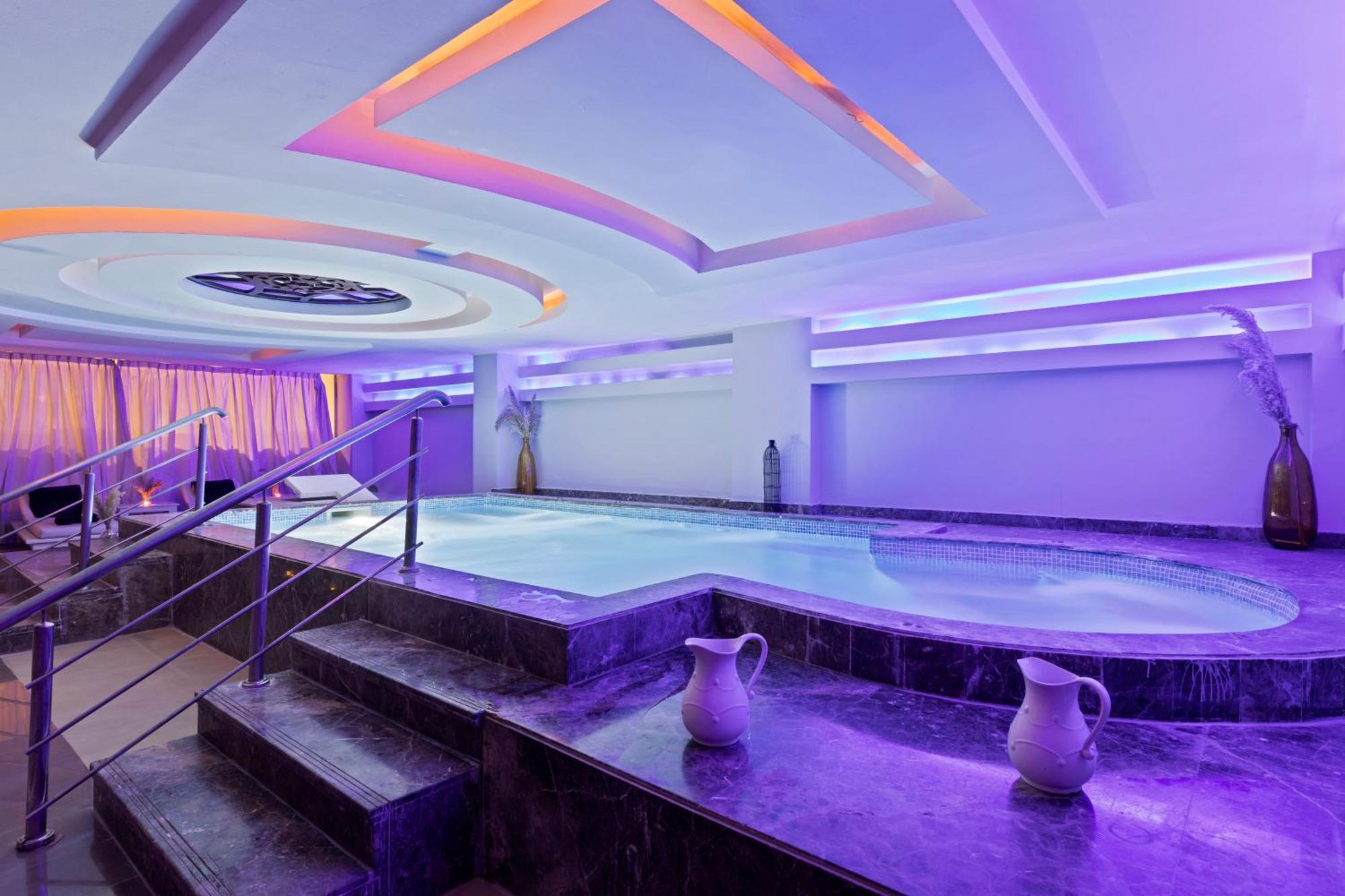 Savoy Le Grand Hotel Marrakech Marakeş Dış mekan fotoğraf The photo shows a modern spa area featuring a small indoor pool or hot tub. The space is illuminated with soft purple and blue lighting, creating a calming ambiance. There are decorative features on the ceiling, and the walls are lined with soft curt