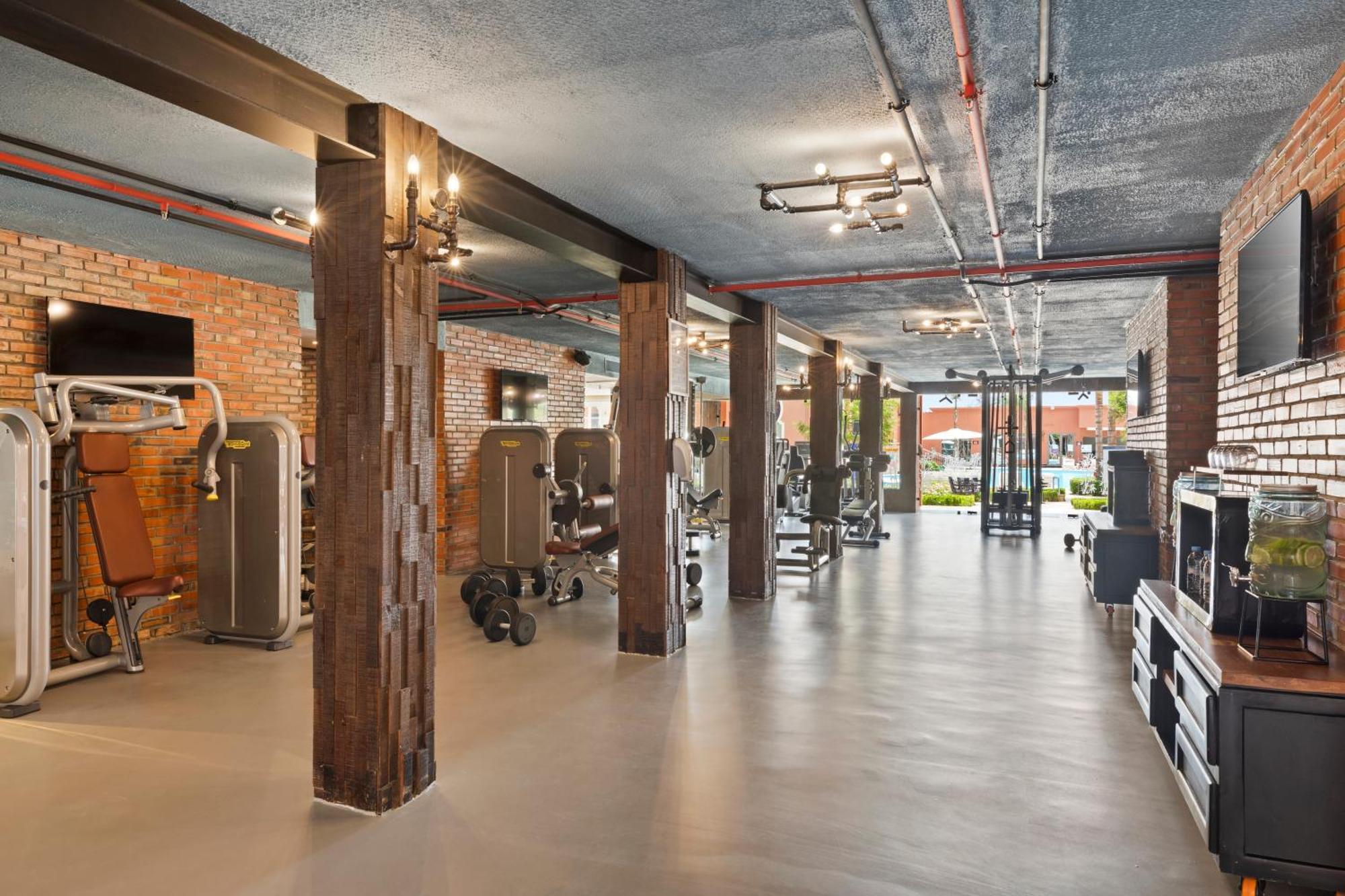 Savoy Le Grand Hotel Marrakech Marakeş Dış mekan fotoğraf The photo shows a modern gym interior with a spacious layout. It features a polished concrete floor and exposed brick walls, giving it a contemporary yet industrial feel. There are various pieces of gym equipment, including weight machines and free w