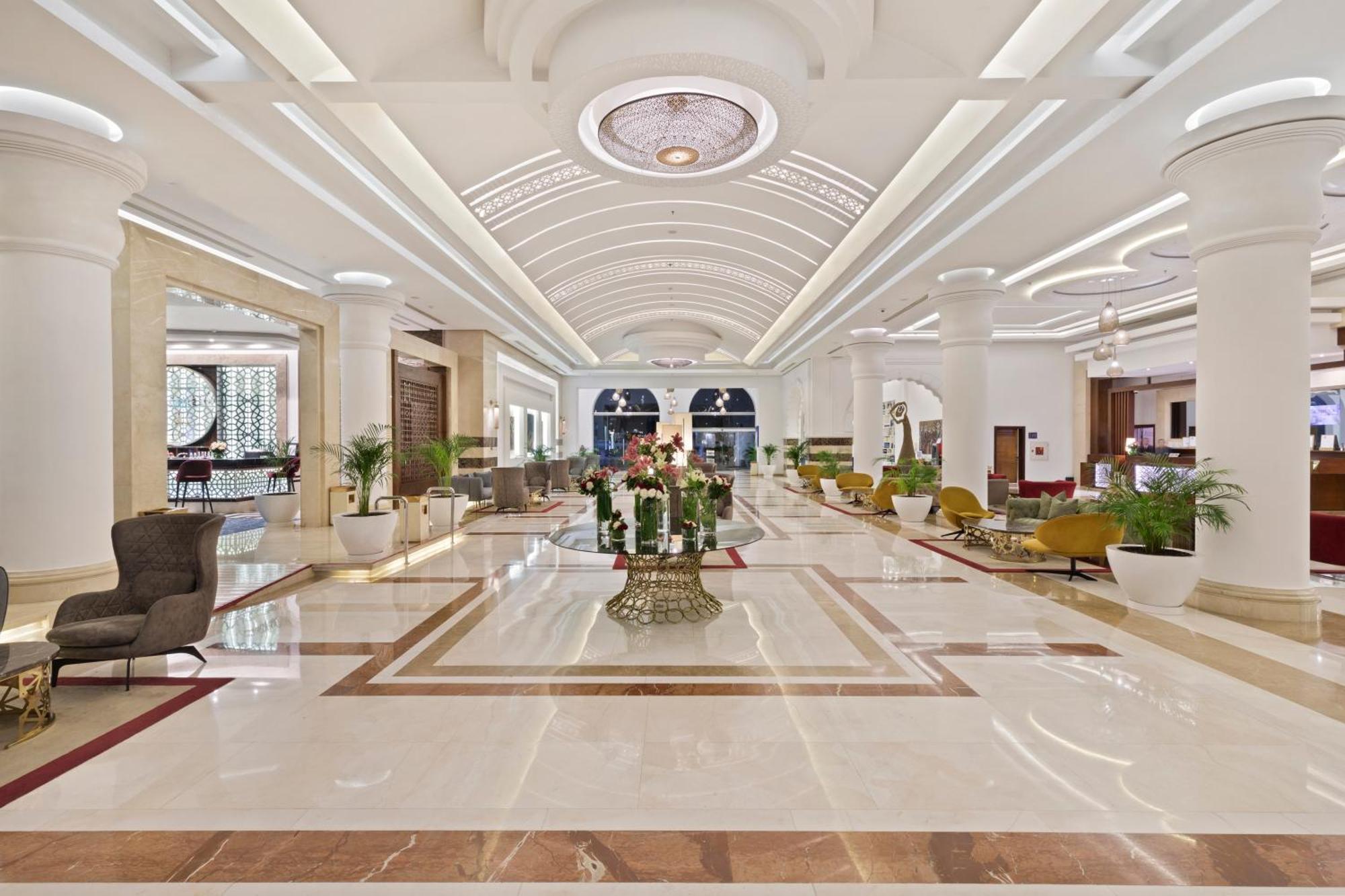 Savoy Le Grand Hotel Marrakech Marakeş Dış mekan fotoğraf The photo shows an elegant hotel lobby. It features a spacious and bright area with high ceilings and well-designed architecture. The floor is polished marble, showcasing a luxurious pattern. There are stylish seating arrangements with various chairs